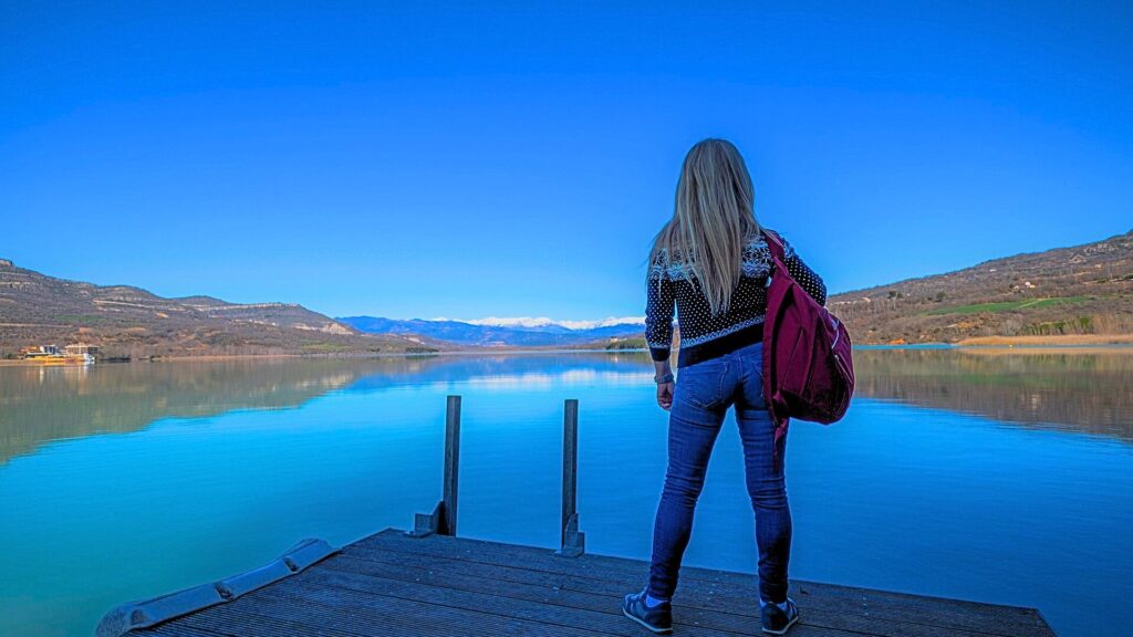 woman with backpack standing on pier